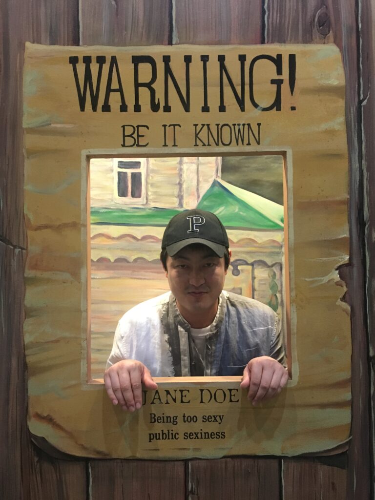 필연적 성공 : 빽빽한 스케줄 보드 앞에 선 민실장과 열정적으로 연기 연습에 매진하는 배우들의 모습이 대비된 강렬한 흑백 이미지